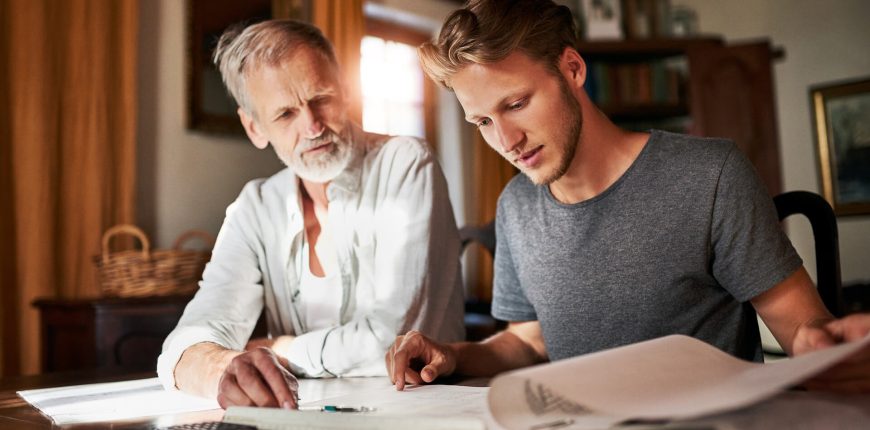 father-and-son-talking-over-paper-work-father-and-son-talking-over-paper-work-iStock-1095307926.jpg