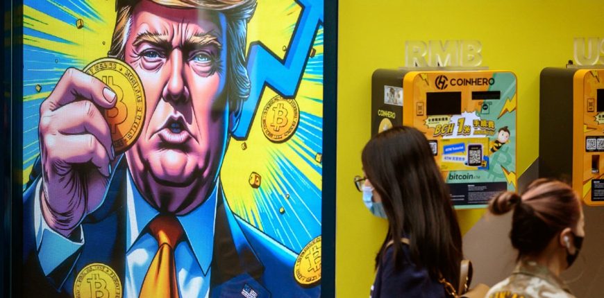 People-walk-past-a-cryptocurrency-exchange-office-with-a-screen-featuring-US-President-Donald-Trump.jpeg