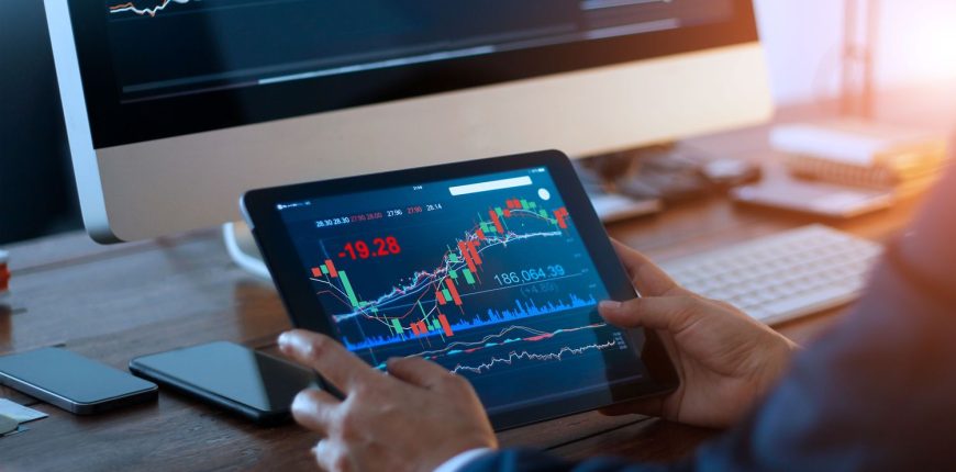 businessman-checking-stock-market-on-digital-tablet-and-a-desktop-computer-with-stock-exchange-graph.jpeg