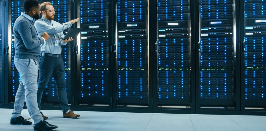 two-software-engineers-walking-down-an-aisle-of-a-data-center.jpg