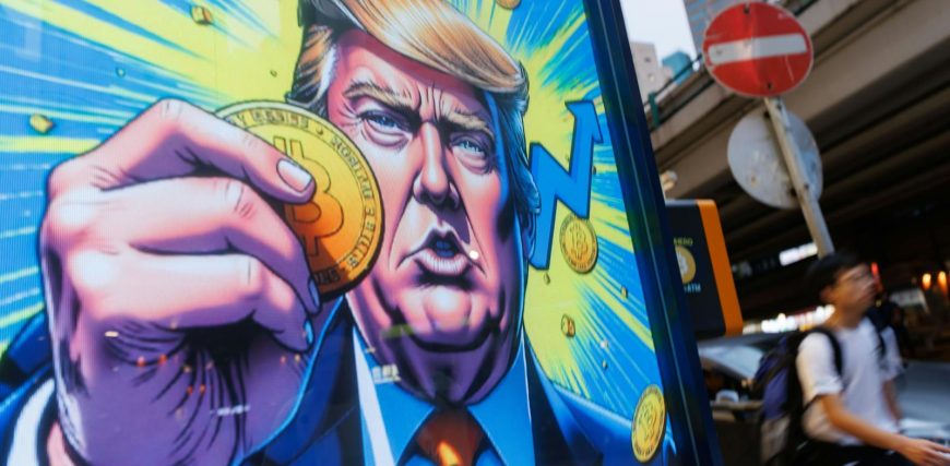 2208409748_people-walk-past-an-advertisement-feature-donald-trump-with-bitcoin-in-hong-kong-on-sunda.jpeg