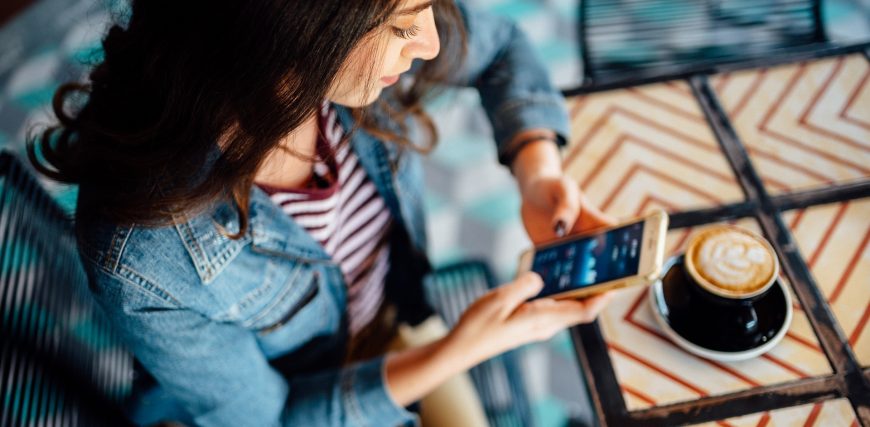 woman-reviews-investments-stocks-on-her-phone-sitting-in-coffee-shop_iStock-1150767833.jpg